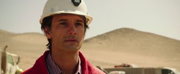 Movie still from “The 33” (2015), directed by Patricia Riggen – A person wearing a hard hat; Close Up shot, Over the shoulder angle