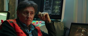 Movie still from “The 33” (2015), directed by Patricia Riggen – An older man sitting in front of a computer screen; Close Up shot, Over the shoulder angle