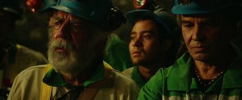 Movie still from “The 33” (2015), directed by Patricia Riggen – A man in a hard hat and a man in a green shirt; Close Up shot, Over the shoulder angle
