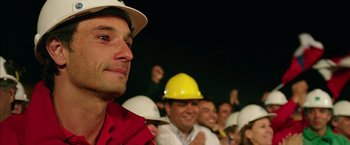 Movie still from “The 33” (2015), directed by Patricia Riggen – A group of people wearing hard hats in a room; Close Up shot, Over the shoulder angle