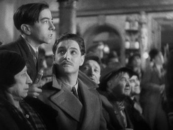 Movie still from “The 39 Steps” (1935), directed by Alfred Hitchcock – Black and white photograph of people in a crowd; Medium shot, Over the shoulder angle