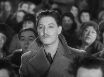 Movie still from “The 39 Steps” (1935), directed by Alfred Hitchcock – A black and white photo of a man in a crowd; Medium shot, High angle