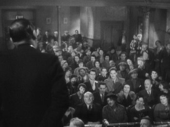 Movie still from “The 39 Steps” (1935), directed by Alfred Hitchcock – An old photo of a group of people sitting in a room; Wide shot, High angle