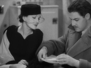 Movie still from “The 39 Steps” (1935), directed by Alfred Hitchcock – A man and a woman sitting at a table with a plate in front of them; Medium shot, High angle