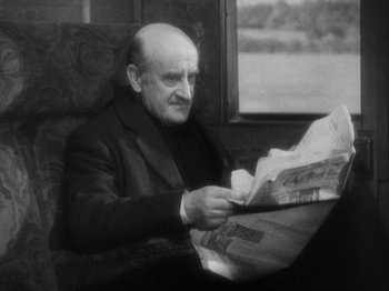 Movie still from “The 39 Steps” (1935), directed by Alfred Hitchcock – An older man sitting in a chair reading a newspaper; Close Up shot, High angle