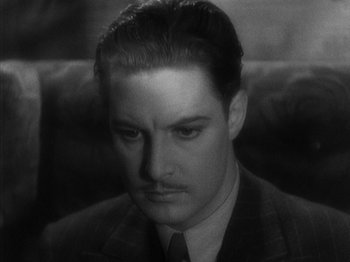 Movie still from “The 39 Steps” (1935), directed by Alfred Hitchcock – A black and white photo of a man in a suit and tie; Close Up shot, High angle