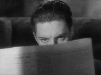 Movie still from “The 39 Steps” (1935), directed by Alfred Hitchcock – A black - and - white photo of a man reading a newspaper; Close Up shot, High angle