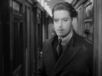 Movie still from “The 39 Steps” (1935), directed by Alfred Hitchcock – A black and white photo of a man in a suit and tie; Close Up shot, High angle