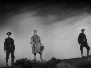 Movie still from “The 39 Steps” (1935), directed by Alfred Hitchcock – A group of men standing on top of a hill; Wide shot, Low angle