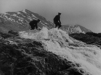 Movie still from “The 39 Steps” (1935), directed by Alfred Hitchcock – Two people standing on a rock near a waterfall; Wide shot, Low angle