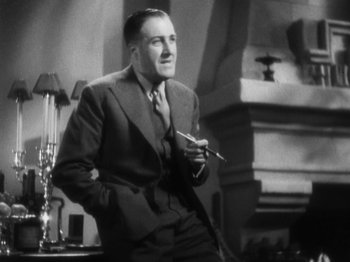 Movie still from “The 39 Steps” (1935), directed by Alfred Hitchcock – An old photo of a man in a suit and tie holding a cigarette; Medium shot, Low angle