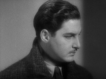 Movie still from “The 39 Steps” (1935), directed by Alfred Hitchcock – A man in a coat and tie looking to his left; Close Up shot, High angle