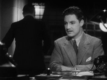 Movie still from “The 39 Steps” (1935), directed by Alfred Hitchcock – A black and white photo of a man sitting at a table; Medium shot, High angle