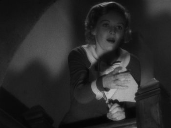 Movie still from “The 39 Steps” (1935), directed by Alfred Hitchcock – A black and white photo of a woman holding a pair of scissors; Medium shot, Low angle