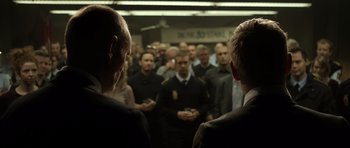 Movie still from “Department Q: The Absent One” (2014), directed by Mikkel Nørgaard – A group of people standing in a room; Medium shot, Over the shoulder angle