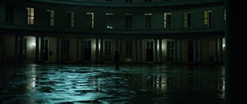 Movie still from “Department Q: The Absent One” (2014), directed by Mikkel Nørgaard – A person walking in the rain in front of a building; Extreme Wide shot, High angle