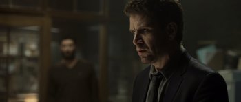 Movie still from “Department Q: The Absent One” (2014), directed by Mikkel Nørgaard – A person wearing a suit and a tie; Medium shot, Over the shoulder angle