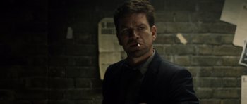 Movie still from “Department Q: The Absent One” (2014), directed by Mikkel Nørgaard – A man in a suit standing in front of a brick wall; Close Up shot, Over the shoulder angle