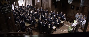 Movie still from “Department Q: The Absent One” (2014), directed by Mikkel Nørgaard – A large group of people sitting at tables in a room; Wide shot, High angle