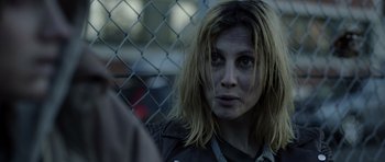 Movie still from “Department Q: The Absent One” (2014), directed by Mikkel Nørgaard – A person near a chain link fence; Close Up shot, Over the shoulder angle