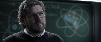 Movie still from “Department Q: The Absent One” (2014), directed by Mikkel Nørgaard – A man with a goatee wearing glasses in front of a chalkboard; Close Up shot, Over the shoulder angle