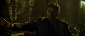 A man in a dark room with his arm outstretched
