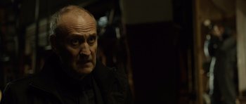 Movie still from “Department Q: The Absent One” (2014), directed by Mikkel Nørgaard – An older man with a goatee stares into the camera; Close Up shot, Over the shoulder angle