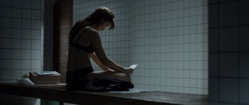 Movie still from “Department Q: The Absent One” (2014), directed by Mikkel Nørgaard – A woman sitting on the ground reading a book; Medium shot, Low angle