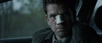 Movie still from “Department Q: The Absent One” (2014), directed by Mikkel Nørgaard – A man with a bandage on his nose; Close Up shot, Over the shoulder angle