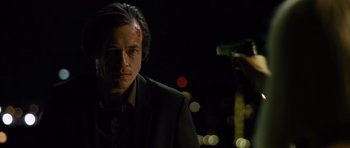 Movie still from “Department Q: The Absent One” (2014), directed by Mikkel Nørgaard – A man in a black suit is holding a gun in his hand; Close Up shot, Low angle