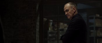 Movie still from “Department Q: The Absent One” (2014), directed by Mikkel Nørgaard – An older man standing in front of a brick wall; Medium shot, Over the shoulder angle