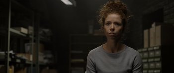 Movie still from “Department Q: The Absent One” (2014), directed by Mikkel Nørgaard – A woman with curly red hair is looking at the camera; Close Up shot, Over the shoulder angle