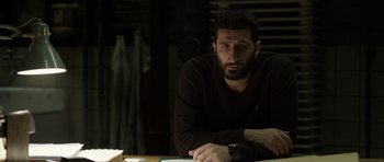 Movie still from “Department Q: The Absent One” (2014), directed by Mikkel Nørgaard – A man sitting at a table in a dark room; Close Up shot, Over the shoulder angle