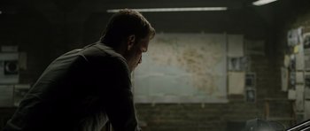Movie still from “Department Q: The Absent One” (2014), directed by Mikkel Nørgaard – A man standing in front of a map in a room; Medium shot, High angle