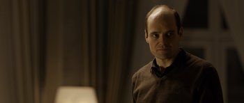 Movie still from “Department Q: The Absent One” (2014), directed by Mikkel Nørgaard – A man in a brown shirt is looking at the camera; Close Up shot, Over the shoulder angle