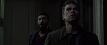 Movie still from “Department Q: The Absent One” (2014), directed by Mikkel Nørgaard – Two men standing next to each other in a dark room; Close Up shot, Low angle