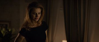 Movie still from “Department Q: The Absent One” (2014), directed by Mikkel Nørgaard – A woman in a black shirt is standing in a room; Medium shot, Over the shoulder angle