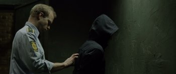 Movie still from “Department Q: The Absent One” (2014), directed by Mikkel Nørgaard – A person in a black hooded jacket and a man in a white shirt; Medium shot, Over the shoulder angle
