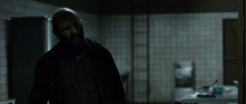 Movie still from “Department Q: The Absent One” (2014), directed by Mikkel Nørgaard – A man standing in the dark in a room; Medium shot, Over the shoulder angle