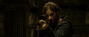 Movie still from “Department Q: The Absent One” (2014), directed by Mikkel Nørgaard – A man holding a gun while wearing a black shirt; Close Up shot, Over the shoulder angle