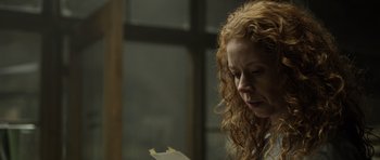 Movie still from “Department Q: The Absent One” (2014), directed by Mikkel Nørgaard – A woman with curly hair is looking down at a piece of paper; Close Up shot, Low angle