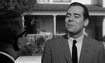 Movie still from “The Absent Minded Professor” (1961), directed by Robert Stevenson – A man in a suit and tie standing in front of a house; Close Up shot, Over the shoulder angle