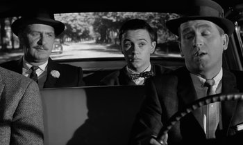 Movie still from “The Absent Minded Professor” (1961), directed by Robert Stevenson – A group of men riding in the back of a car; Medium shot, Over the shoulder angle