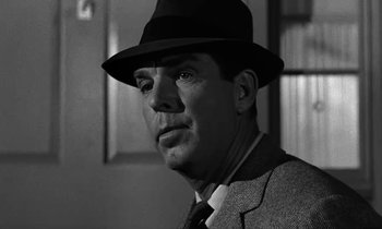 Movie still from “The Absent Minded Professor” (1961), directed by Robert Stevenson – A black and white photo of a man wearing a suit and a hat; Close Up shot, Over the shoulder angle
