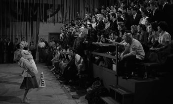 Movie still from “The Absent Minded Professor” (1961), directed by Robert Stevenson – A group of people sitting in the bleachers watching a game; Wide shot, High angle