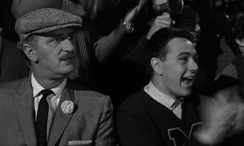 Movie still from “The Absent Minded Professor” (1961), directed by Robert Stevenson – Two men sitting next to each other in front of a crowd; Close Up shot, Low angle