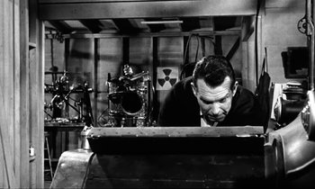 Movie still from “The Absent Minded Professor” (1961), directed by Robert Stevenson – A black and white photo of a man looking down at a keyboard; Medium shot, Low angle