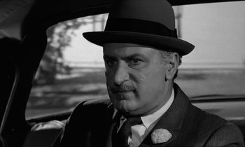 Movie still from “The Absent Minded Professor” (1961), directed by Robert Stevenson – An older man wearing a suit and a hat; Close Up shot, Over the shoulder angle