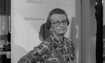 Movie still from “The Absent Minded Professor” (1961), directed by Robert Stevenson – An older woman wearing glasses standing in front of a white door; Close Up shot, Low angle