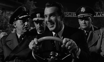 Movie still from “The Absent Minded Professor” (1961), directed by Robert Stevenson – A group of men standing next to each other in front of a car; Close Up shot, Over the shoulder angle